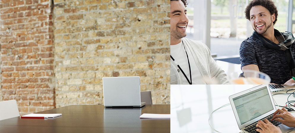 Image of stock laptop at a conference table, two men laughing and someone typing on a laptop