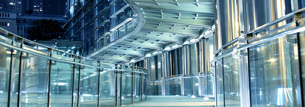 Modern glass building walkway at night with illuminated steel architecture, corporate office exterior and urban city design scene