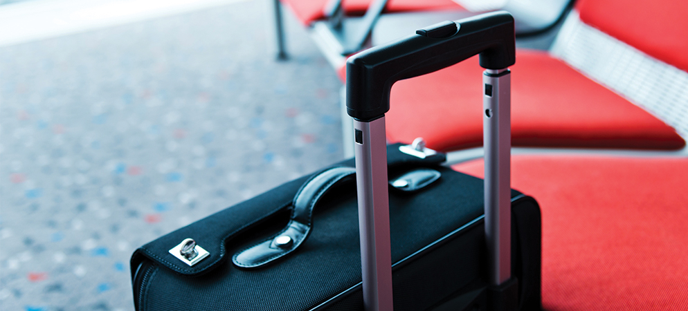 Carry-on suitcase with telescopic handle next to airport waiting seats, travel luggage ready for flight departure and business trip journey