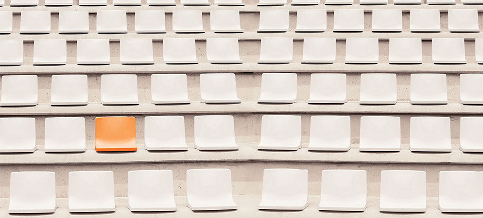 Rows of empty stadium seats with one orange chair, venue seating pattern and standout seat concept for events