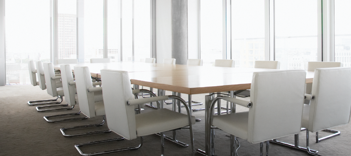 Empty modern conference room with long boardroom table and white chairs, bright windows, corporate meeting space ready for collaboration.