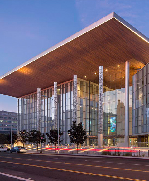 Modern glass civic building with dramatic cantilever roof at dusk, contemporary architecture and urban streetscape exterior