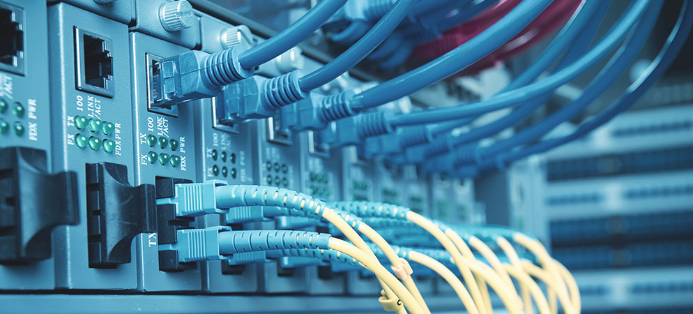 Close-up of network switch with Ethernet and fiber optic cables connected in a data center server rack for high-speed connectivity