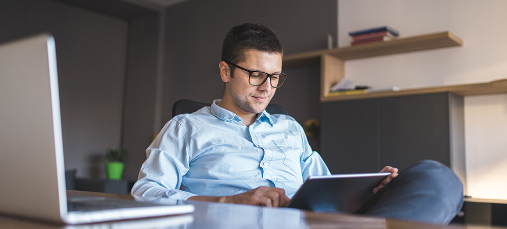 Man working from home on tablet at desk, remote employee using digital device for online work and productivity