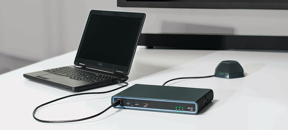 Laptop connected to Biamp Devio conference hub and tabletop microphone on meeting room table for professional audio and video conferencing setup