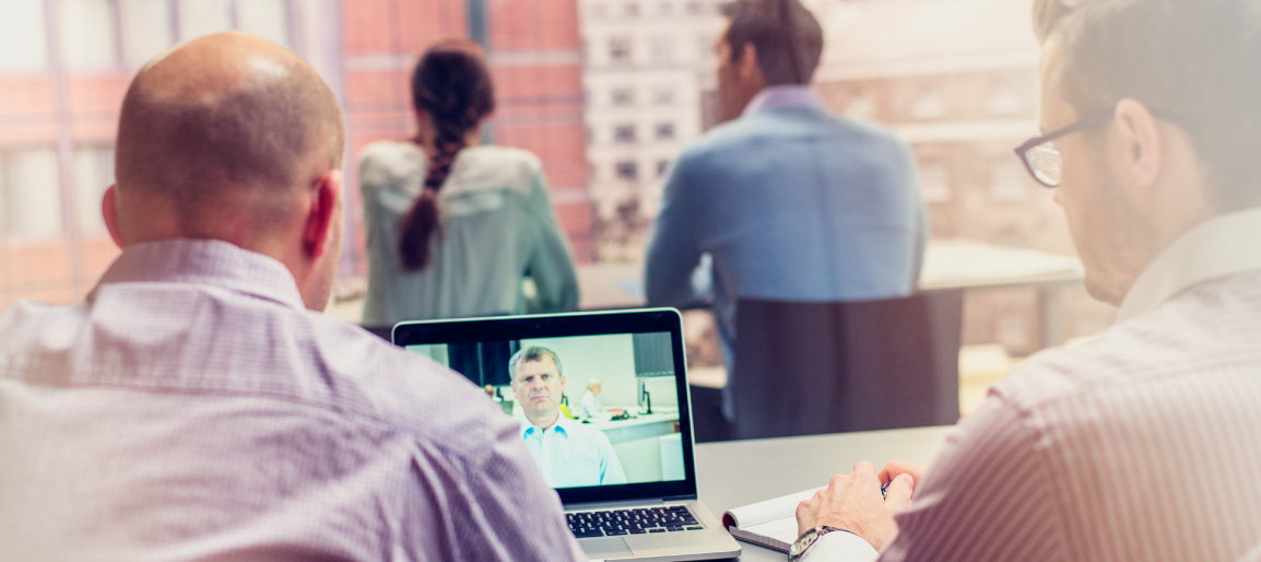 Business team in office using laptop for video conference call, collaborating with remote colleague in modern workspace with city view