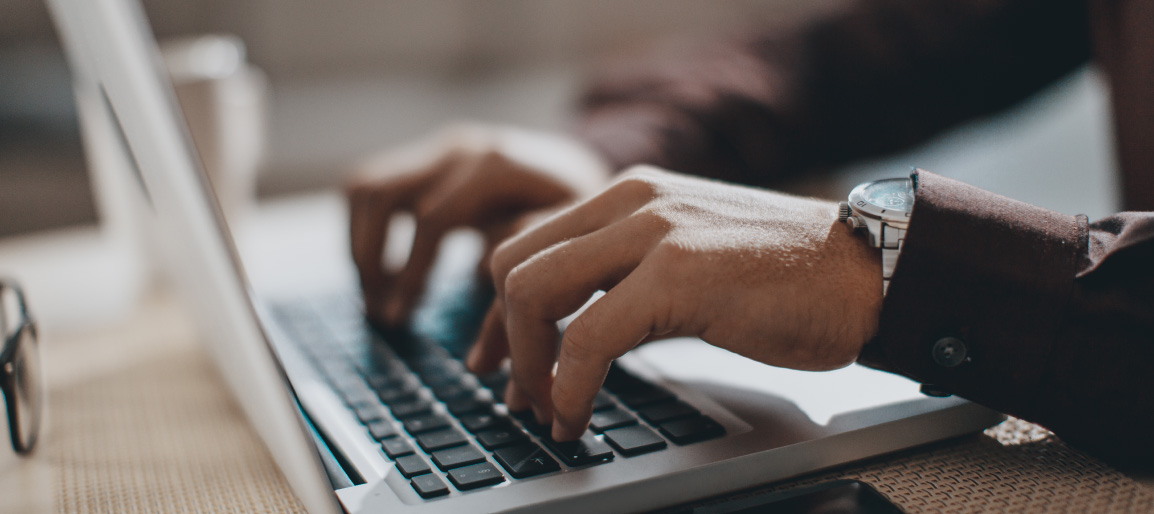 Close-up of hands typing on laptop keyboard, business professional working remotely with focused productivity and office technology setup