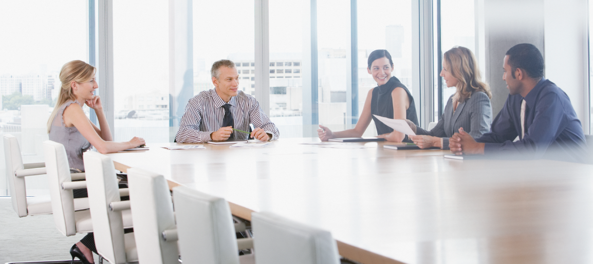 Business team meeting in bright modern conference room with large table and city view, collaborating on strategy and documents
