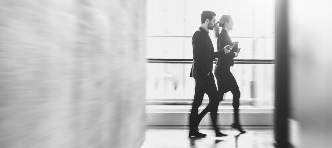 Blurred business colleagues walking in modern office corridor, black and white photo conveying workplace motion, commute, and corporate lifestyle