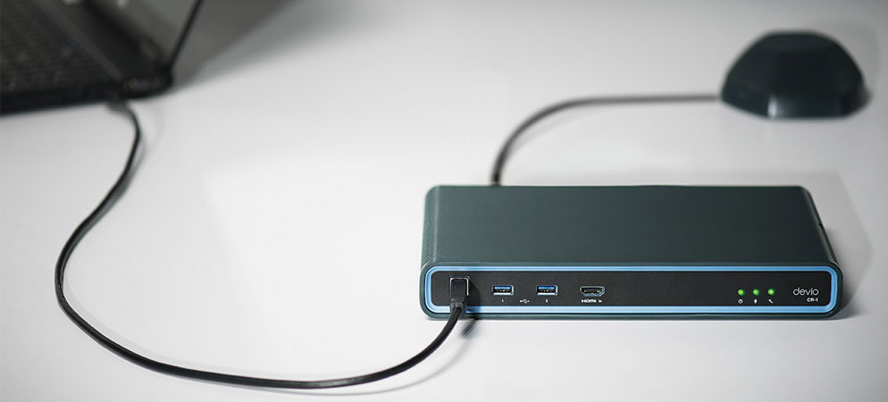 Biamp Devio CR-1 conference hub connected to laptop and tabletop microphone, featuring USB and HDMI ports for meeting room AV integration