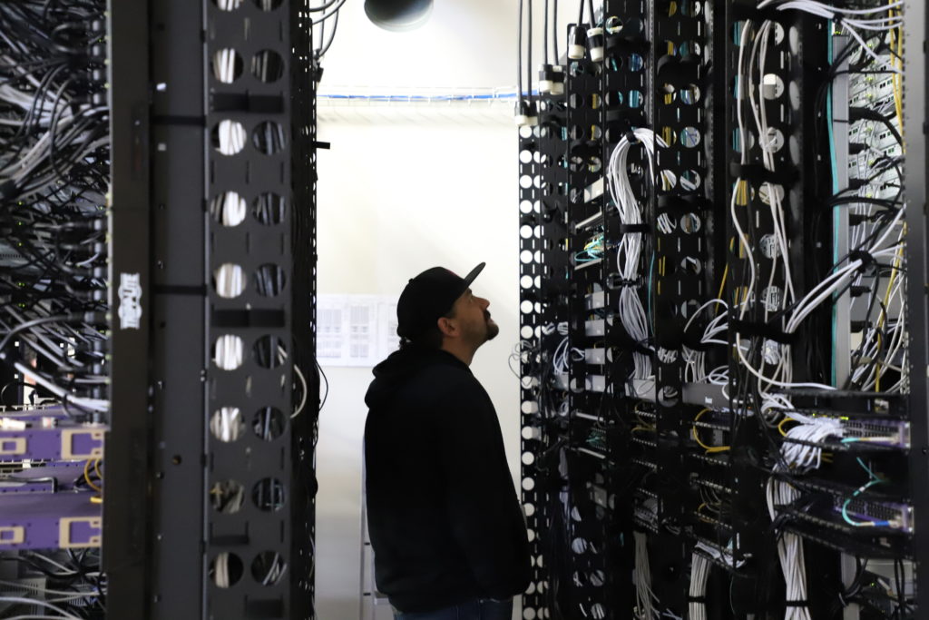 Image of a person looking at a wiring server rack.