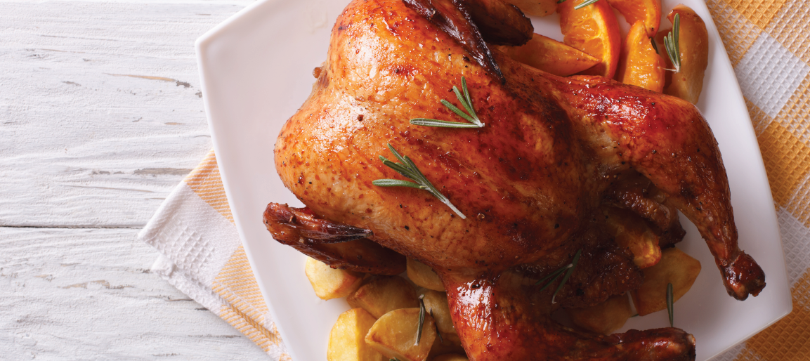Roast chicken on platter with crispy skin, rosemary, roasted potatoes, and citrus slices on rustic table, perfect family dinner meal