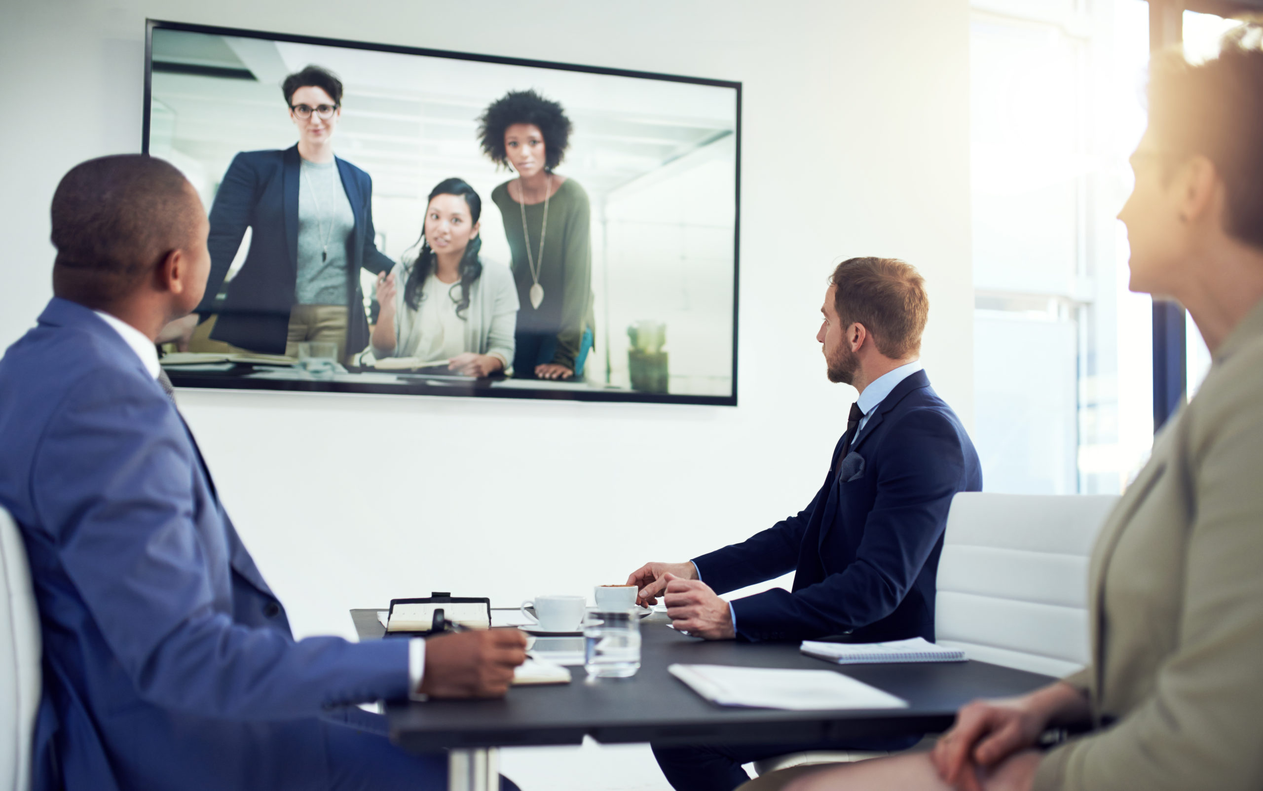 Business team in conference room watching video call on large display for hybrid meeting collaboration and remote presentations