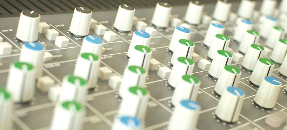 Close-up of audio mixing console knobs and controls for sound engineering, live audio mixing, and recording studio equipment