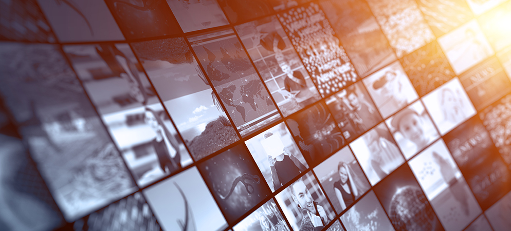 Digital media wall mosaic of images and videos with warm light flare, representing multimedia content, broadcasting, and news streaming platform