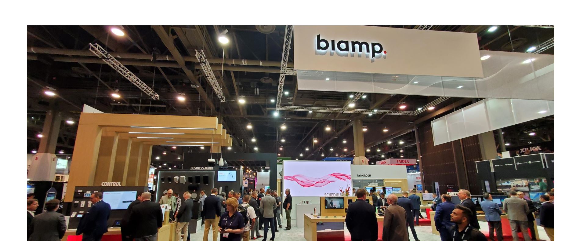 Biamp Infocomm 2024 trade show booth at AV expo with attendees exploring conferencing, control, and business audio solutions on showroom floor