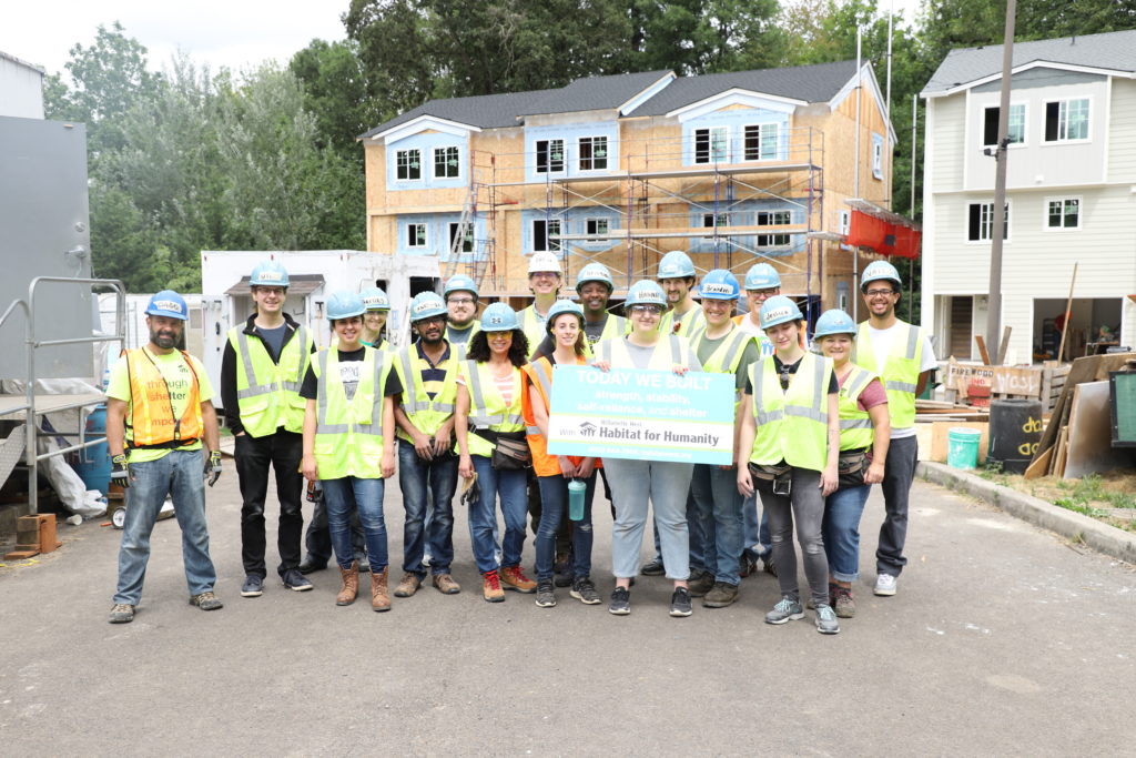 Image of a group of people with construction gear on holding a large check for Habitat for Humanity.
