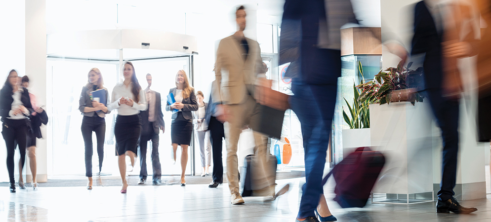 Blurred business people walking through modern office lobby, conveying busy corporate workplace, commuting professionals, and fast-paced workday movement