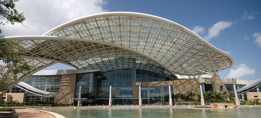 Modern convention center exterior with curved glass roof and entrance, event venue architecture for conferences and trade shows