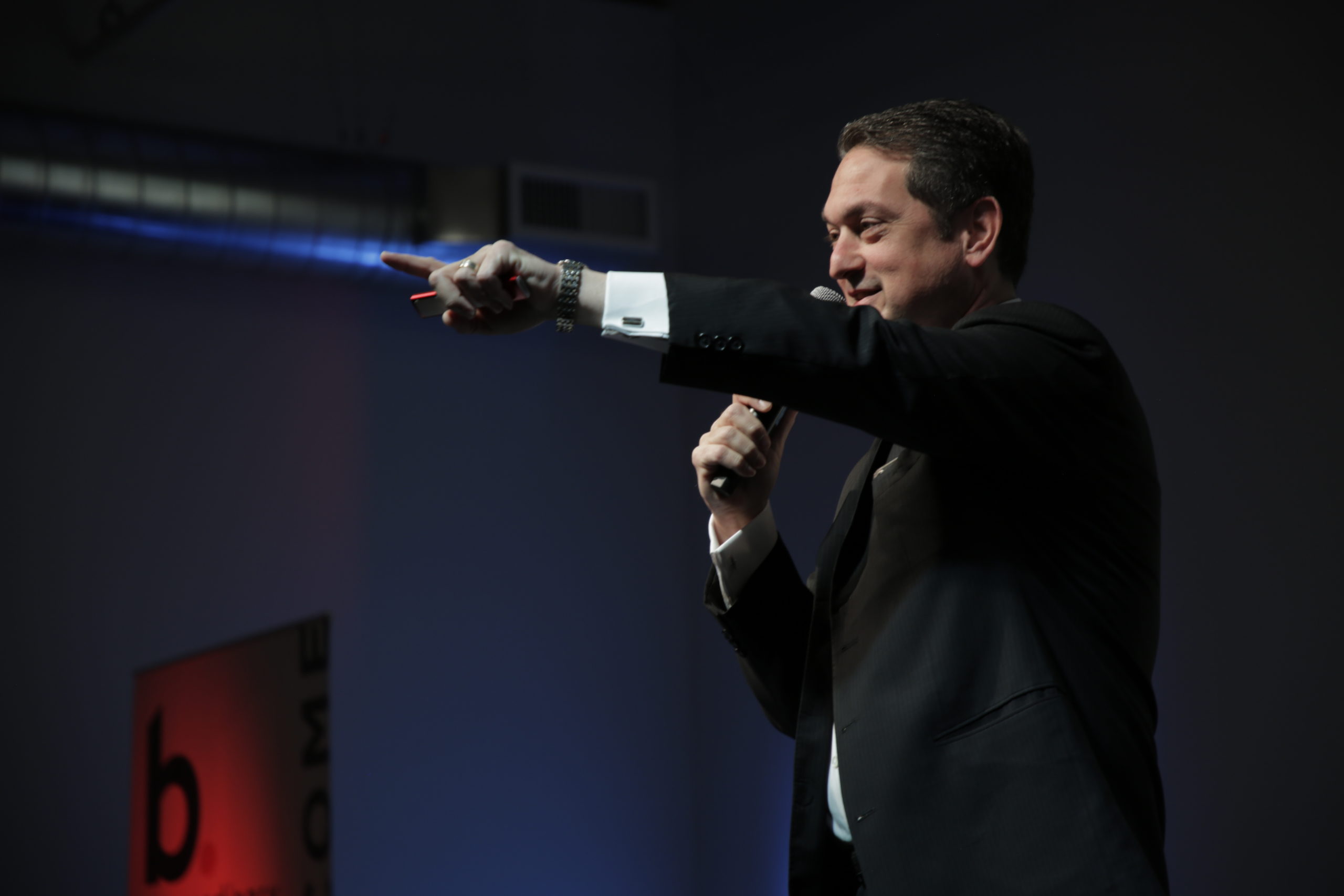 Biamp CEO and Co-Chairman, Rashid Skaf pointing out into an audience with a microphone in hand.