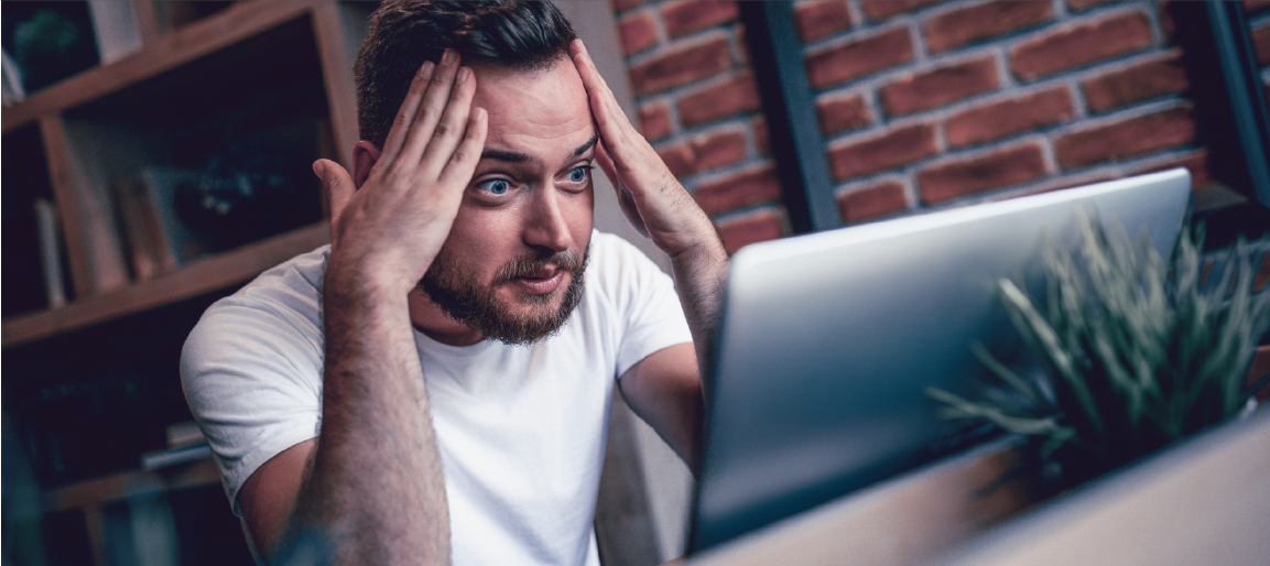 Stressed man holding his head while looking at laptop in home office, workplace burnout and deadline pressure concept, frustrated employee.