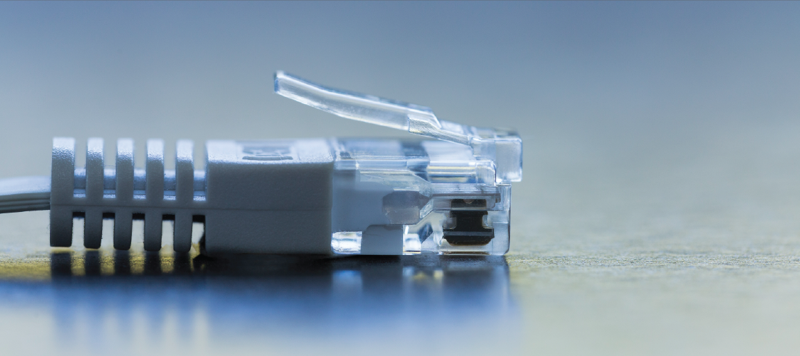 Close-up of RJ45 Ethernet cable connector on desk, showing network plug details for internet, LAN, and data communication setup