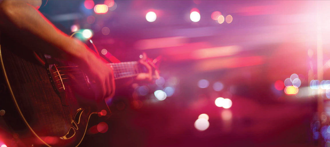 Close-up of guitarist playing electric guitar on stage with colorful concert lights and bokeh, live music performance atmosphere
