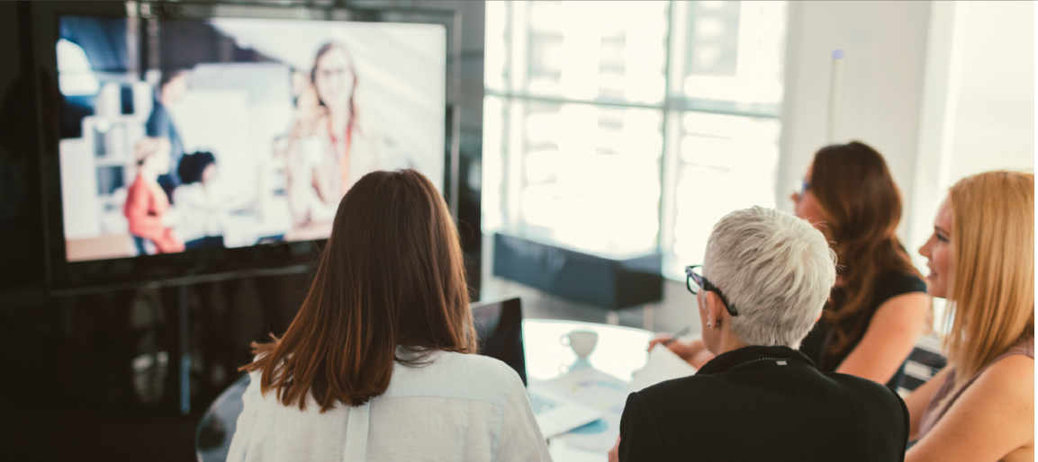 Team in modern meeting room using video conferencing on large screen, remote collaboration for business presentation in bright office.