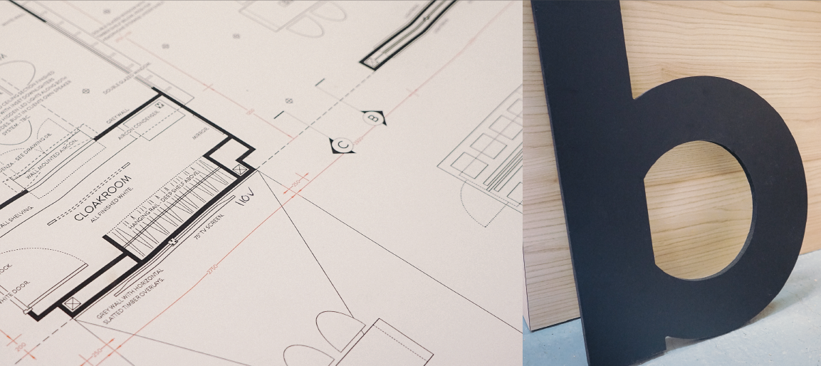 Architectural floor plan blueprint on desk beside large “b” sign, building design layout and construction planning concept for workspace project.