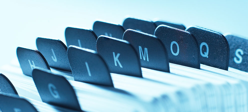 Close-up of alphabetical file index tabs for document organization, office filing system, and records management concept