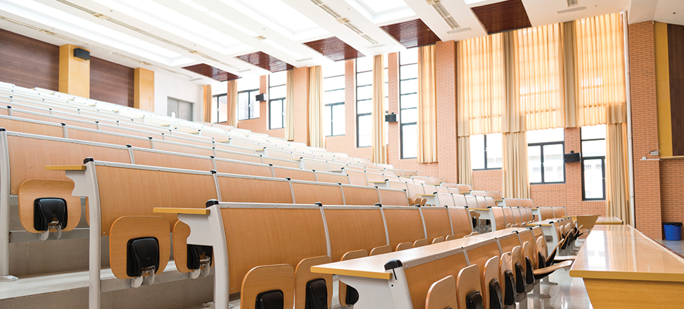 Empty university lecture hall classroom with tiered seating and desks, bright windows and modern interior, education auditorium space.