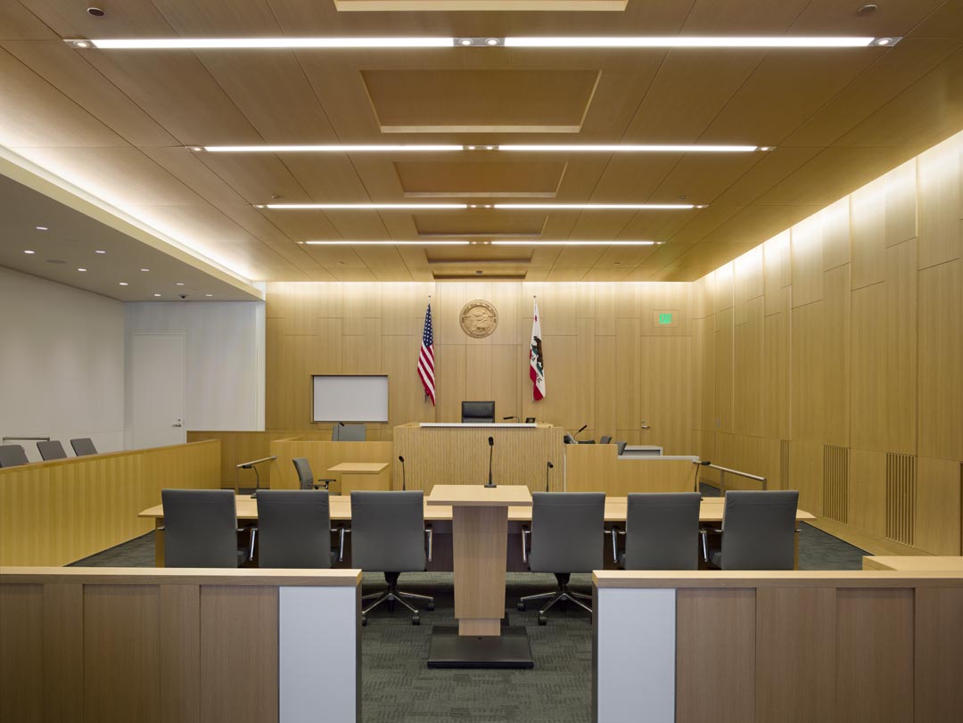 Empty modern courtroom interior with judge’s bench, jury seating, and flags, legal courthouse hearing room design