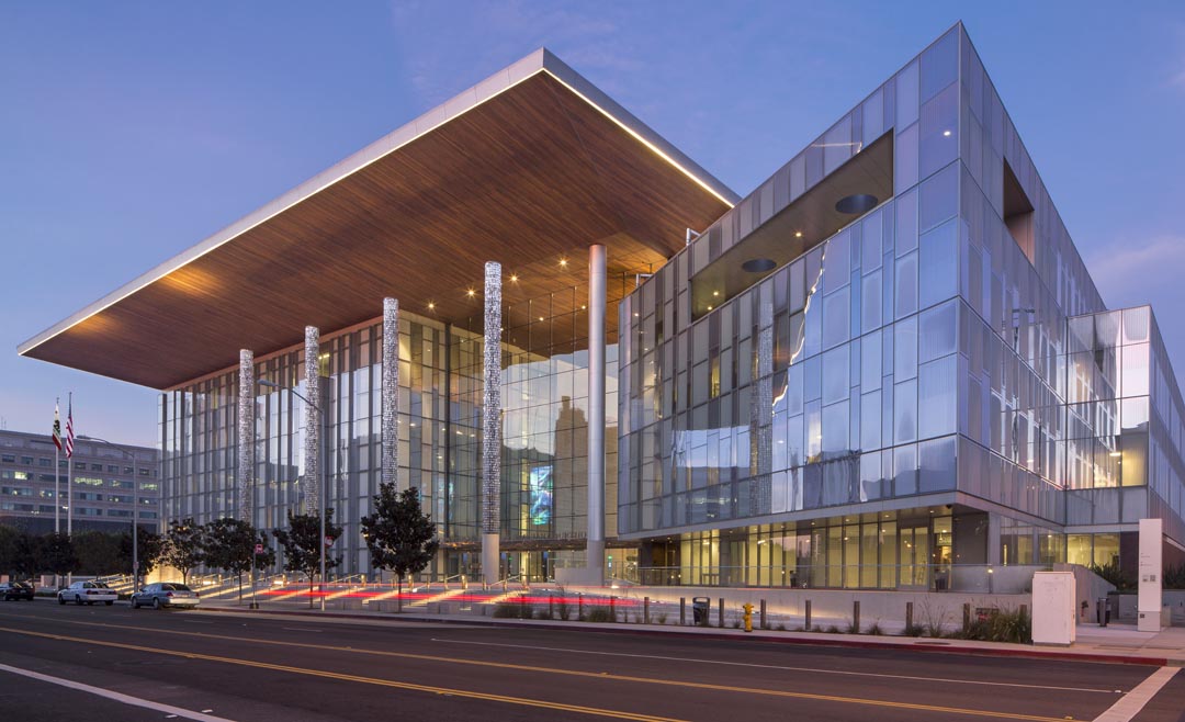 Modern civic building exterior at dusk with glass facade and large cantilever roof, contemporary architecture and urban cityscape