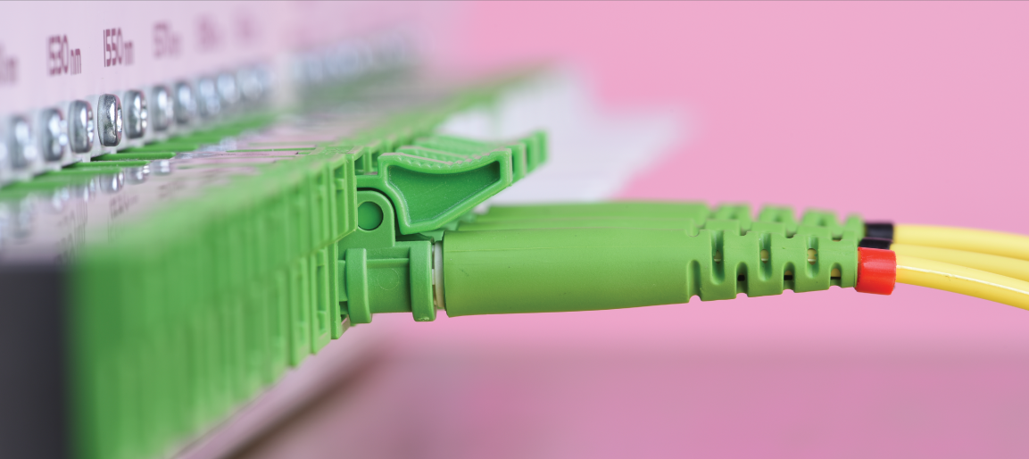Close-up of fiber optic connector plugged into AV patch panel, highlighting high-speed AV cabling