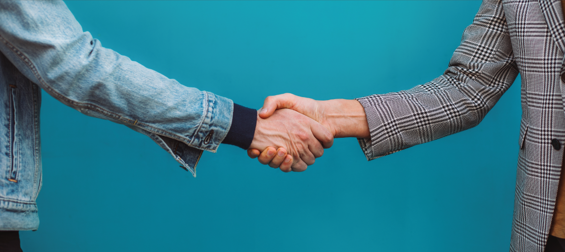 Close-up handshake between two people on teal background, symbolizing business partnership, agreement, and professional networking deal