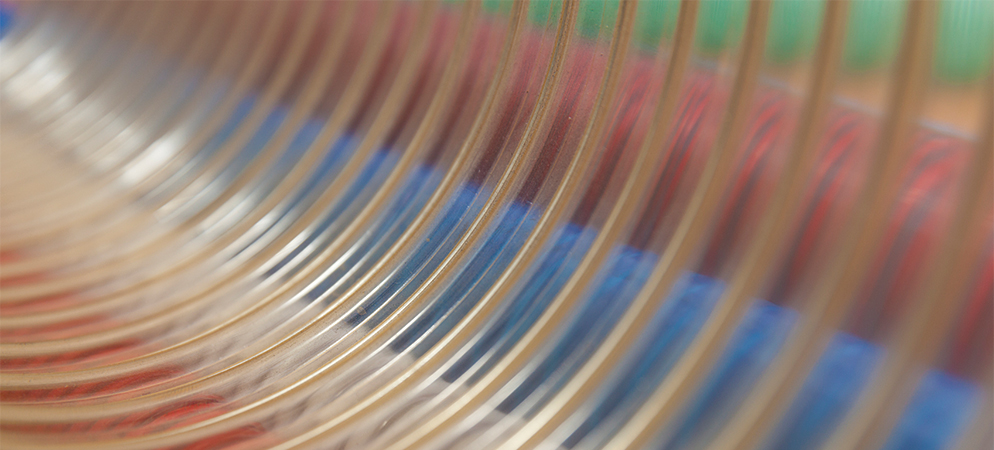 Abstract close-up of curved glass or acrylic surface with colorful reflections, creating modern textured background for design and technology themes