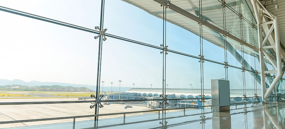 Modern airport terminal interior with large glass windows overlooking runway, travel infrastructure and transportation hub architecture