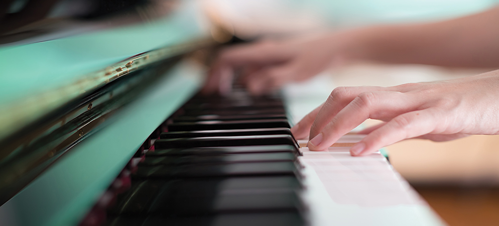 Close-up of hands playing piano keys, capturing musician performing on keyboard instrument with soft focus and motion blur