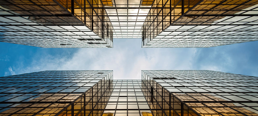 Upward view of modern glass office skyscrapers with blue sky, corporate architecture and commercial building exterior design
