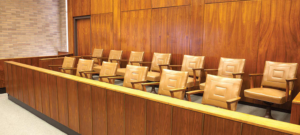 Empty jury box seating in courtroom with wood paneling and chairs, legal trial and justice system interior scene