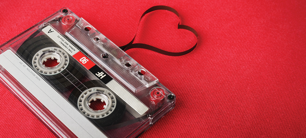 Vintage audio cassette tape on red fabric with tape shaped like a heart, retro music media concept and nostalgia background.