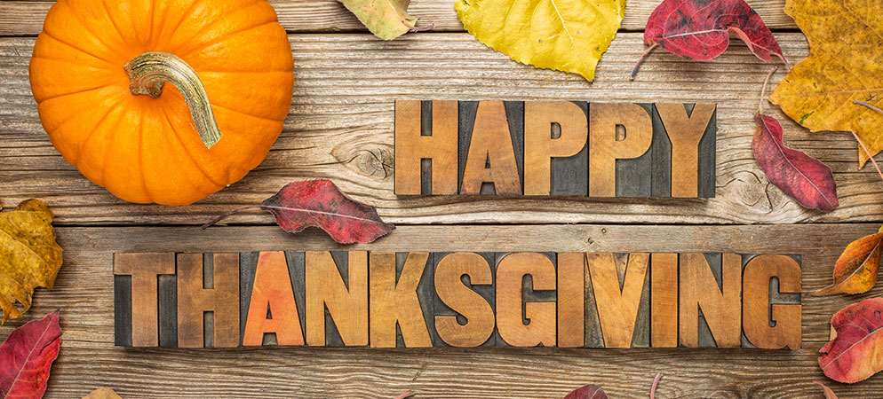Happy Thanksgiving greeting with pumpkin and autumn leaves on rustic wood background, seasonal holiday message banner