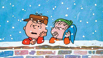 Image of Charlie Brown and Linus leaning on a low wall in the snow talking.
