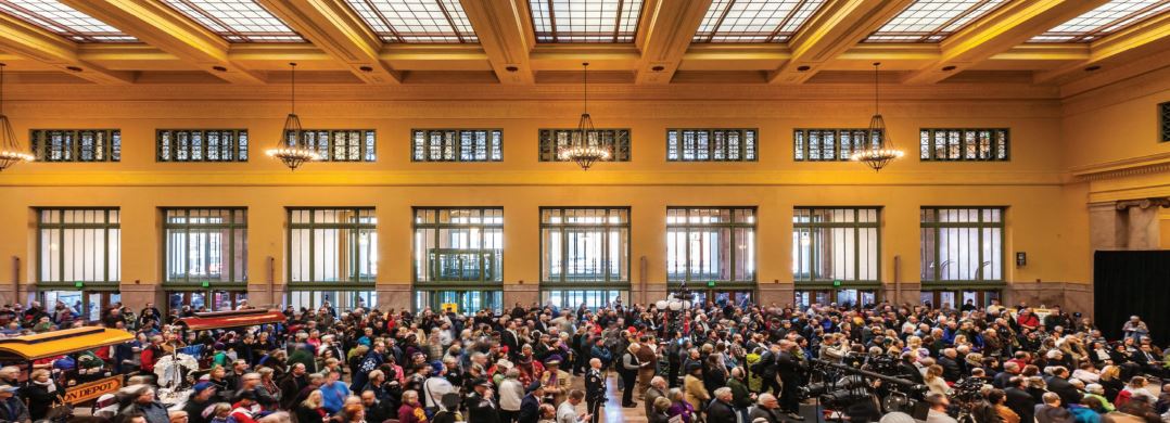 Crowded indoor event hall with large audience gathered under high ceiling, public gathering and conference venue atmosphere
