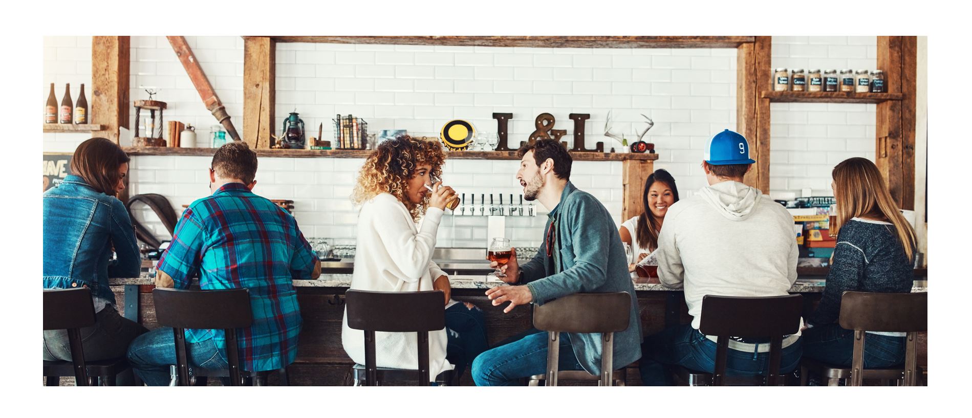 Friends socializing at modern bar with craft beer taps, casual nightlife scene in restaurant and brewery setting