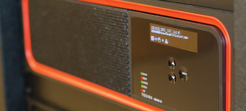 Close-up of Biamp Tesira rack-mounted DSP front panel with LCD status screen, navigation buttons, and LED indicators for AV system control