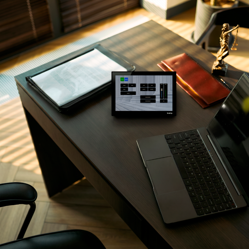 Desk with laptop Biamp Control panel and binder and justice scales