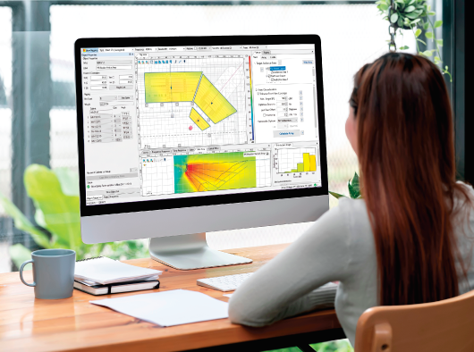 Person using venue audio design software on desktop monitor with polar coverage mapping and acoustic analysis tools displayed