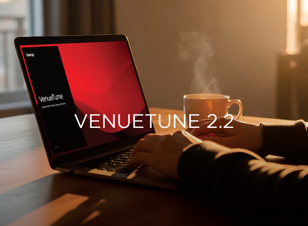 VenueTune 2.2 software shown on laptop with user working at desk beside steaming coffee cup