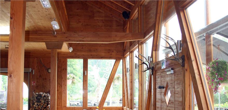 Rustic restaurant interior with exposed wooden beams, antler decor, and large windows.